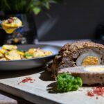 Tasty meatloaf with egg centerpiece served with potatoes. Perfect for a hearty meal.