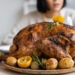 Palatable roasted turkey with potatoes and lemon on wooden round tray placed on table for celebrating Thanksgiving Day