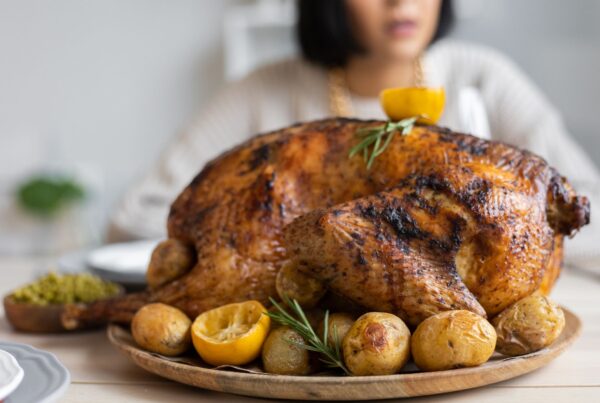 Palatable roasted turkey with potatoes and lemon on wooden round tray placed on table for celebrating Thanksgiving Day