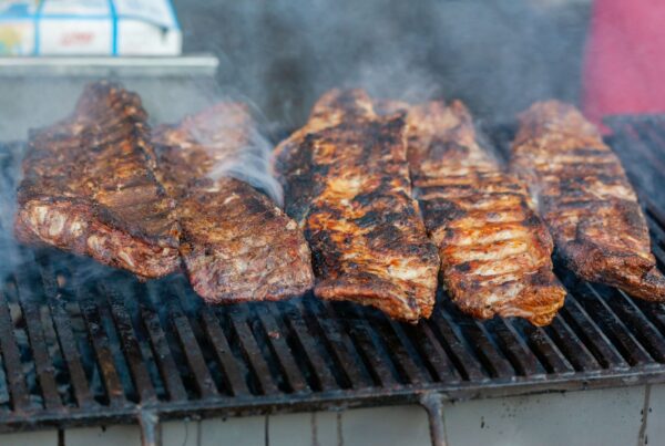 Close-up of delicious grilled ribs smoking on a barbecue grill, perfect for a summer cookout.